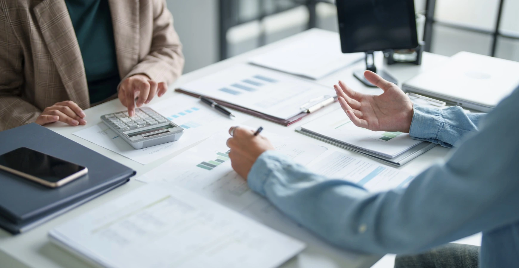 Two business professionals reviewing data charts and financial reports during a corporate financial services consultation meeting.